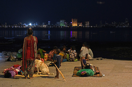 Homeless people are seen on the beach as the cityscape is clearly visible behind them due to improved air quality in Mumbai. Air quality improved drastically after a spell of unexpected rain in the city.