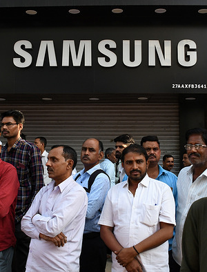 People are seen standing below a Samsung logo in Mumbai.