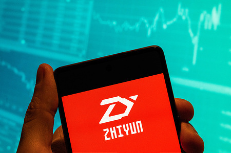 In this photo illustration, the Chinese video gimbal stabilizers manufacturer Zhiyun Tech logo seen displayed on a smartphone with an economic stock exchange index graph in the background.