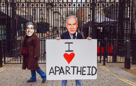 Amnesty International UK activists wearing Benjamin Netanyahu and Rishi Sunak masks stand outside Downing Street with an 'I Love Apartheid' placard during a protest as the Israeli Prime Minister visits the UK.