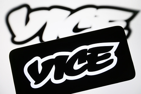 In this photo illustration, Vice Media Group logo is seen on a smartphone and on a pc screen.