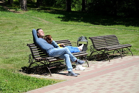 A couple seen relaxing on a bench and enjoying the sun in the Kislovodsk National Park, Russian Federation. Kislovodsk National Park is a specially protected natural area in the city of Kislovodsk. The largest city park in Europe. The area is 965.8 hectares.