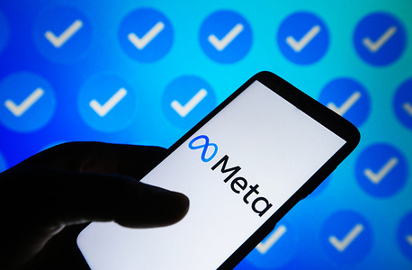 In this photo illustration, Meta logo is seen on a smartphone and blue verification badges on a pc screen.