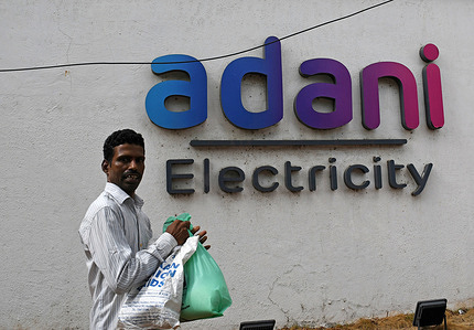 A man walks past the Adani electricity logo on the wall in Mumbai. Adani power and energy is one of India's largest power distribution company which is a part of Adani group of companies.