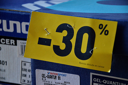 In this photo illustration a yellow label indicating a 30% discount is seen on a box of sports shoes. The summer sales ended on August 1, 2023 in metropolitan France.