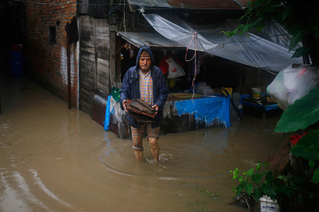 A man carrying leftovers outside her shop wades through flooded homes after heavy rainfall in Kathmandu. Kathmandu, Nepal experienced severe flooding, resulting in widespread damage and disruption. Heavy rainfall led to overflowing rivers and waterways, inundating streets, homes, and infrastructure. The flooding has caused significant challenges for local residents and authorities, prompting emergency response efforts to provide relief and support to those affected.