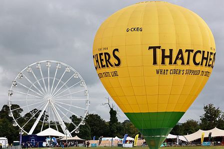 A balloon with a Thatcher's cider logo on it seen on the grass. Bristol International Balloon Fiesta is Europe's largest hot air balloon meeting, attracting over 100 hot air balloons from around the world. In addition to watching balloons, there are also different activities, such as large-scale rides and booth activities.