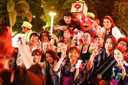 Crowd members pose for photographs at the culmination of the Japan Bon Dance Festival in Cairns. The Japanese Bon Festival is a festival to honor the spirits of ancestors. Cairns Japan Bon Dance Festival is a free event co-organized by the Japanese Society of Cairns and The Consular Office of Japan in Cairns and supported by the Cairns Regional Council. The festival showcases Japanese traditional activities, including Japanese drumming, Bon dances, and J-pop music performances.