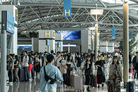 Tourists with suitcases walk in front of check-in counters information at Incheon International Airport.