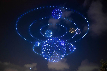 Drones light show, forming a solar system in space over Victoria Harbour in Hong Kong, with one drone falling to the bottom left. 800 drones were seen in the sky as part of Hong Kong's recently announced Waterfront Carnival. Intended to help boost the local economy, the Carnival featured musical performances, food, and product vendors. DMD Digital Art, the company presenting the light show, managed the technical feat of launching, maneuvering, and then landing hundreds of drones. Shortly after 8pm, the machines lit up and a buzz filled the air. The drones flew together to form moving images such as shooting stars, a swimming whale, and a revolving solar system, before landing back in their boxes. Alas, one drone wouldn't make it back as it plunged into the water. "I was nervous,” said Justin Yeung, Project Manager for DMD. “It was the first time we flew them over Victoria Harbour!” With most of the drones safely on the ground, he and his team celebrated with high fives and selfies and prepared for the next night's show.