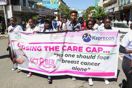 People walk while holding a banner during a cancer awareness walk in Nakuru Town. In Nakuru town, people came together to march through the streets, raising awareness about breast cancer in honor of World Cancer Awareness Month, also known as Pink October. They emphasized the importance of regular health check-ups and screenings for early cancer detection and treatment.
