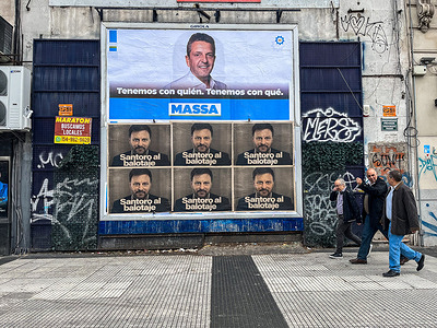 People walk past political signs of Sergio Massa, along the streets of Buenos Aires. Argentine presidential elections will be held on October 22, 2023.
