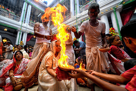An Indian Hindu woman sits with burning fire pots on her hands and head as part of their ritual practice which includes blind faith and superstition to overcome every difficulties in coming future during the Maha ashtami celebration on the 8th day of Durga puja. Durga puja is the biggest Hindu festival running for 9 days all over India.