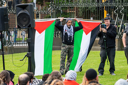 A protester holds two Palestine flags during a rally in Melbourne. In a heartfelt gathering in Melbourne Australia , Jews and their allies came together to protest the ongoing Israeli military action in Gaza. The devastating loss of thousands of innocent lives has spurred their call for immediate peace. Holding signs and chanting slogans, they made a powerful plea for international intervention, urging world leaders to prioritize diplomacy over violence.