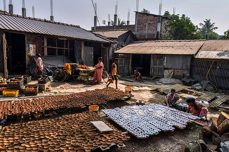 A pottery family is busy sorting and coloring earthen lamps in the pottery village named Chaltaberia, around 40km outskirts of Kolkata in West Bengal. The entire village is in full rhythm of earthen lamp and idol production ahead of the Diwali festival in India. Earthen lamps sold in all over Indian cities like Kolkata, Delhi, Mumbai, Hyderabad, Gujarat, Assam, Patna, and Rajasthan, especially during festival season. Even earthen lamps are being exported to outside of India ahead of Diwali celebrations.