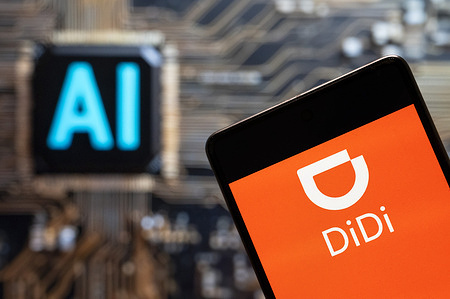 In this photo illustration, the Chinese ride-sharing company, Didi logo seen displayed on a smartphone with an Artificial intelligence (AI) chip and symbol in the background.