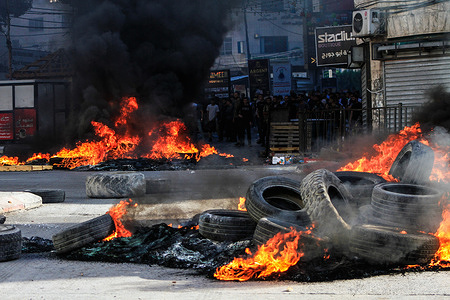 View of burning tires in the middle of the road during a bloody raid at Jenin refugee camp. Israeli forces raided Jenin refugee camp in the West Bank, which led to an exchange of fire between armed Palestinian resistance fighters and the Israeli forces. Young Palestinian men demonstrated, burned tires everywhere, and the raid continued for more than 12 hours. 14 Palestinians were shot dead by Israeli forces and many were injured.