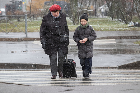 People walk along the city streets during snowfall in St. Petersburg.