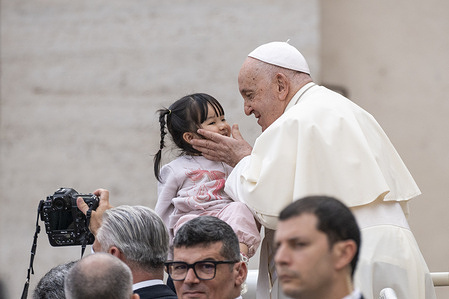 Pope Francis kisses a child as he leaves St. Peter's Square after leading his traditional Wednesday General Audience.