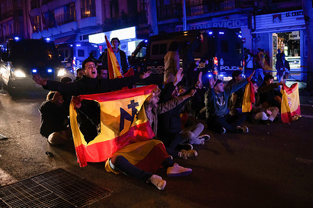 A group of demonstrators sit in the middle of the street confronting police during the 14th day of violent protests in Madrid against the investiture of Pedro Sanchez and the amnesty. More than 3,000 people gathered on Thursday 17 November in Madrid's Calle Ferraz on the night of the investiture of Pedro Sánchez, who was re-elected president of Spain. For the fourth night in a row, clashes broke out between far-right demonstrators and police. They ran through the streets of Madrid, broke some glass and set fire to a rubbish bin.