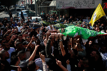 (EDITOR'S NOTE: Image depicts death) Mourners carry the bodies of three Palestinians draped in the Hamas and Islamic Jihad militant group flags during their funeral in the Jenin refugee camp. Israeli forces killed three Islamic jihad Palestinian men in an overnight raid, the Palestinian Health Ministry said this Friday. The military wing of the Palestinian Islamic Jihad group claimed the bodies of the three, including local commander Jamal Lahlouh, 23, as members.