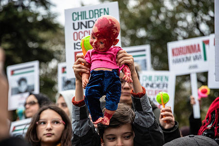 A child seen holding a doll painted with fake blood during the demonstration. A protest was held in Istanbul to draw attention to the deaths of children in Palestine on the occasion of World Children's Day. According to recent reports, there are over 13,000 Palestinians who died during the Israel-Hamas war, which includes over 5,000 children.