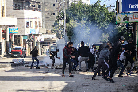 Palestinian youths throw stones at Israeli military vehicles in Balata refugee camp during a raid to arrest wanted Palestinians, east of Nablus in the northern West Bank.