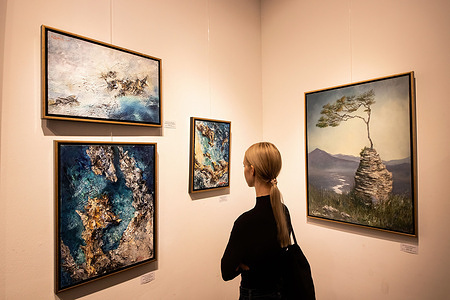 A visitor examines the paintings during the vernissage. Vernissage at the business art gallery in the Artmuza museum. Exhibition of a series of works entitled 'Blurring Borders' by the artist Erokhina Ekaterina at the Artmuza Museum in St. Petersburg.