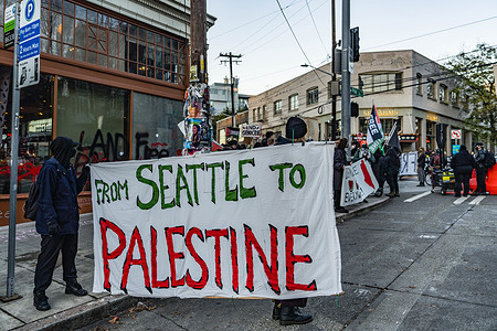 Protesters hold a banner outside Starbucks during the demonstration. A gathering of pro-Palestinian supporters convened at the first Starbucks Reserve Roastery located in Seattle's lively Capitol Hill neighborhood. The event, marked by demonstrations, saw various signs and messages displayed prominently. Among the numerous signs carried by the demonstrators, one read, "Stand with Palestine! End the occupation now!" while others proclaimed, "Palestine will be free!"