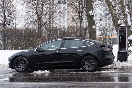 A Tesla car is charged from a city charging station on a street in Moscow. Since 2020, the city's charging stations have been part of the city's complex electrical infrastructure.