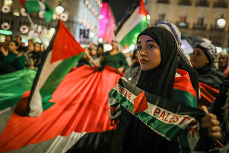 A protester holds a scarf in colors of the Palestinian flag during a pro-Palestinian rally in Madrid's Puerta del Sol. A protest was organized with the slogan "29-N: no to the partition of Palestine" on November 29th, the International Day of Solidarity with the Palestinian People. This day marks the UN Assembly's 1947 approval of Resolution 181, which led to the partition of Palestine and the establishment of Israel.