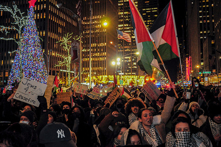 Protesters crowd the streets while holding Palestinian flags and placards expressing their opinion during a rally. Thousands of protesters gathered outside the News Corp. building in Manhattan, New York City, and demanded a permanent ceasefire in the war between Israel and Hamas. The rally occurred at the end of a two-day extension of a truce in the war between Israel and Hamas.