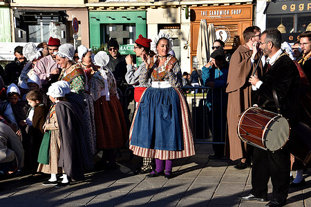 A female folk dancer in traditional Provençal costume dances while clapping her hands. A group of Provençal folk dancers offers a performance to visitors to the Foire aux Santons in Marseille.