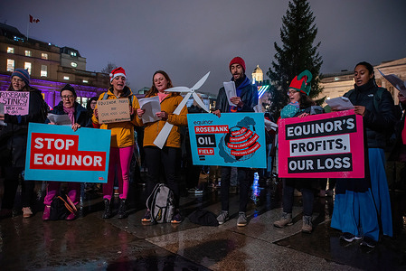 Protesters sing Christmas carols while holding placards during the protest on the Trafalgar Square in London. Extinction Rebellion activists organized a demonstration during the official Christmas lights ceremony to protest Norway-based Equinor's plans to develop the Rosebank oil field in the UK.