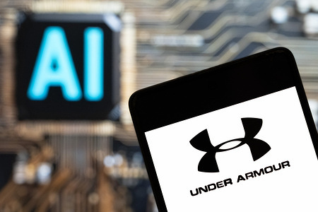 In this photo illustration, the American multinational clothing brand Under Armour (NYSE: UAA) logo seen displayed on a smartphone with an Artificial intelligence (AI) chip and symbol in the background.