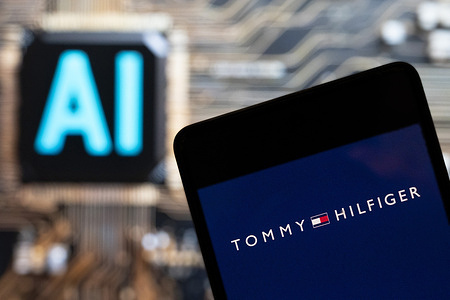 In this photo illustration, the American fashion brand Tommy Hilfiger logo is seen displayed on a smartphone with an Artificial intelligence (AI) chip and symbol in the background.