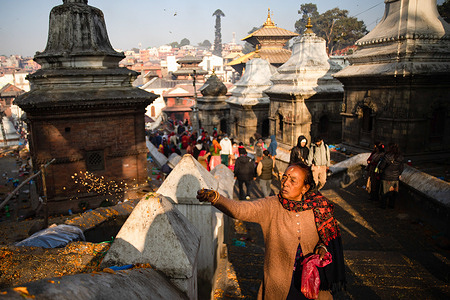 A Hindu devotee scattering seven types of grains known as "sat biu" along a route at the Pashupati temple to honor the departed during Bala chaturdashi Festival. Nepalese Hindu Devotees celebrate the festival by lighting oil lamps and scattering seven types of grains known as "sat biu" along a route at the temple to honors the departed.