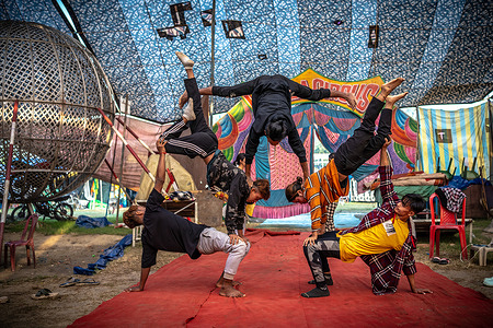 Circus performers from Manipur, practice their stunts inside of a circus tent before the final performance. The changing times have severely impacted the once-vibrant circus industry. Ceasing animal shows and transitioning solely to human acts, circus owners confront declining demand and a sharp decrease in ticket sales. This shift has sparked a lack of interest among newer generations, threatening the circus business and its cherished traditional entertainment legacy.