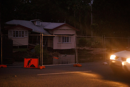 Headlights reveal a partially collapsed house in Holloways Beach, a Cairns suburb that was totally inundated with flood water since Sunday.