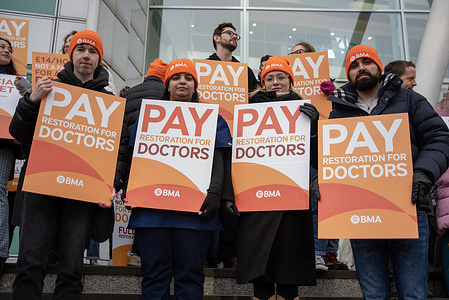 Protesters hold placards outside the University College Hospital in London, UK. BMA (British Medical Association) says the junior doctors' pay has been cut by more than a quarter since 2008/9. Because of that they strike for full pay restoration.