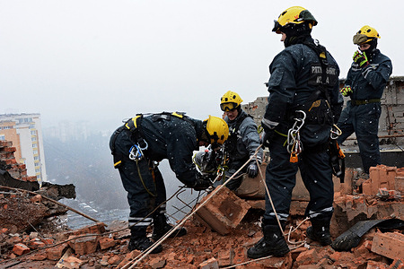 Workers of the Municipal Emergency and Rescue Service (KARS), stand on the roof of a drone-damaged high-rise residential building in Solomyanskyi district. Early this morning, Russian forces launched an attack on the Ukrainian capital using kamikaze drones, which were intercepted by the Ukrainian Air Defense Forces. Despite interception efforts, fragments from these drones caused damage to structures in several districts of the city.