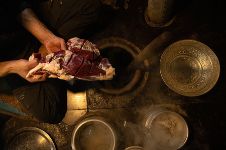 A Kashmiri chef puts meat in an earthen pot to prepare Harisa on a cold day in Srinagar. Harisa is a centuries-old traditional delicacy breakfast dish that keeps the body warm all day to assist people endure the freezing conditions. It is mostly composed of sheep meat, spices, aromatics, and rice flour. It takes around 12 hours to cook and must be stored overnight in an underground earthen pot with steam until squashy before consumption. This dish is typically eaten in the early morning with freshly made bread. Historians believe that Harisa was introduced to Kashmir in the 14th century by Persian Sufi scholar Mir Syed Ali Hamdani.