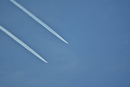 Two airliners fly in parallel in the airspace, leaving white trails in the sky.