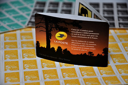 In this photo illustration, the la poste book seen on top of yellow 0.01 euros stamps The French national postal service, "La Poste," has declared an increase in stamp prices effective from January 1, 2024. This adjustment involves the timbre vert or green stamp, which will rise from €1.16 to €1.29.