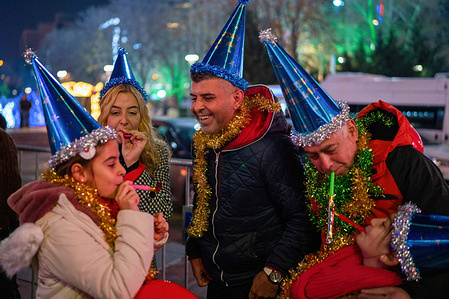 A family wearing party hats seen during the New Year celebration. Crowds assemble for the New Year festivities held at Kızılay Square, the heart of Ankara, Turkey's capital city.