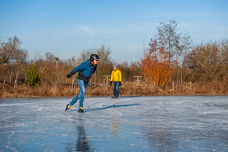 Two men are seen skating on ice. After several days of sub-zero temperatures (around -8 degrees Celsius during the night), the water of some lakes started to freeze over. As the wintry weather continued, some skaters took the chance to skate in one of the frozen lakes close to the Dutch city of Nijmegen.