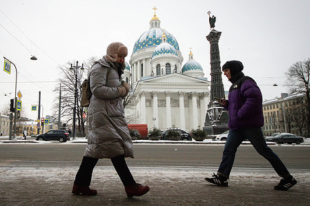 People walk along the city streets against the backdrop of the Trinity Cathedral in St. Petersburg.