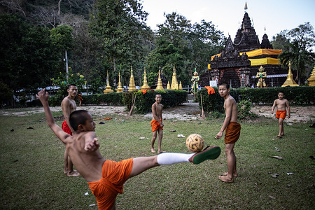 Local and Burmese monks play football in the late afternoon at the Wat Tham Pla Temple. Wat Tham Pla (Cave Fish Temple) is also referred to as the "Monkey Temple" for Thai locals, located 16 kilometers from Mae Sai, the northernmost city of Thailand.