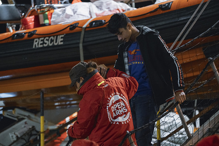 A member of Open Arms helps a migrant to disembark. The rescue vessel of the Spanish Non-governmental organization (NGO) Open Arms arrived in Crotone with 57 migrants onboard, including 5 minors saved between Italy and Libya.