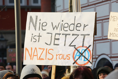 A placard reading " Nazis out" and "never again means now" is held high during a demonstration. Protesters and organizations such as the Greens and Fridays for Future gather to protest against the right-wing meeting held recently near Potsdam. The meeting included AFD members and plans were discussed to deport citizens who have failed to integrate into life in Germany.